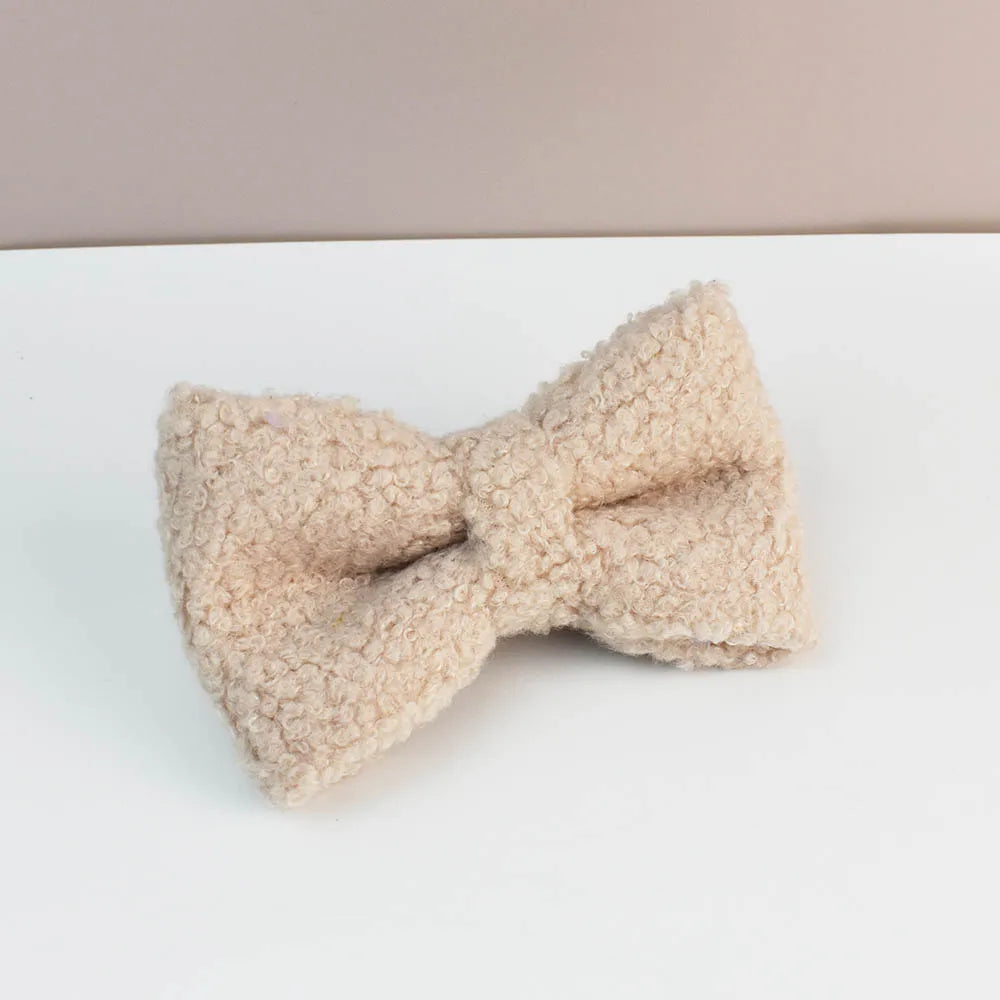Beige dog bow accessory on a white surface with a beige background