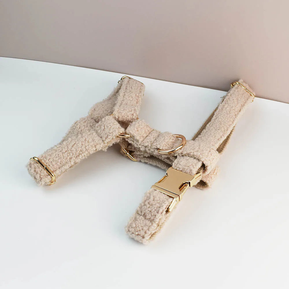 Beige pet harness with gold hardware on a white surface
