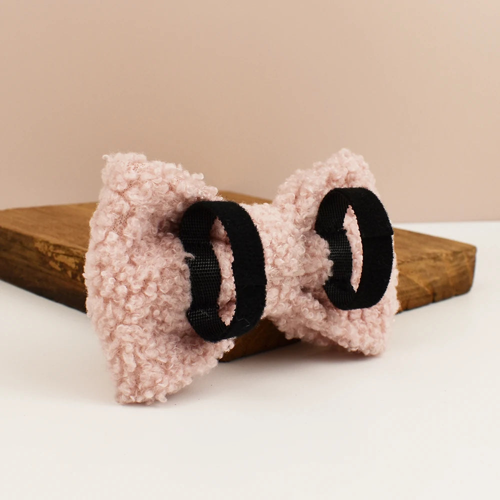 Pink fuzzy hair bow with black elastic on a beige background