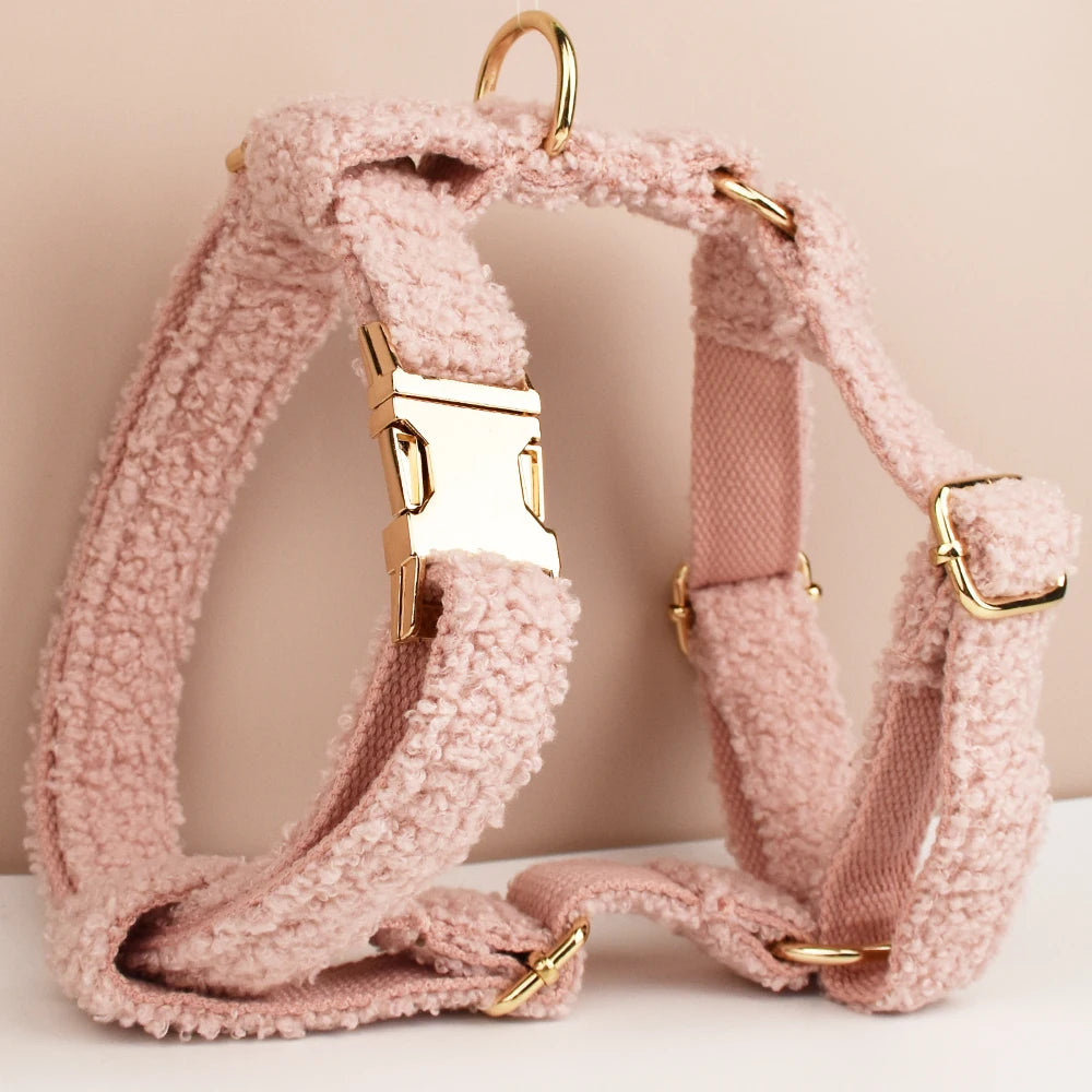 Pink dog harness with gold hardware on a light background