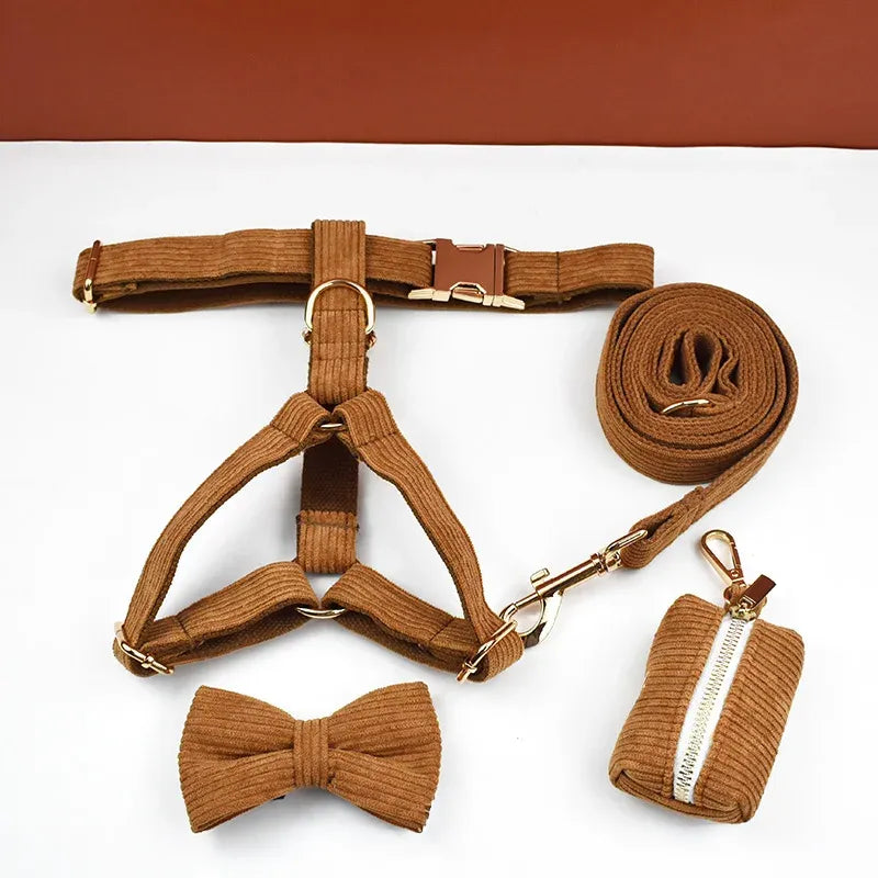 Brown dog harness, bow tie, leash, and poop bag set on a white background