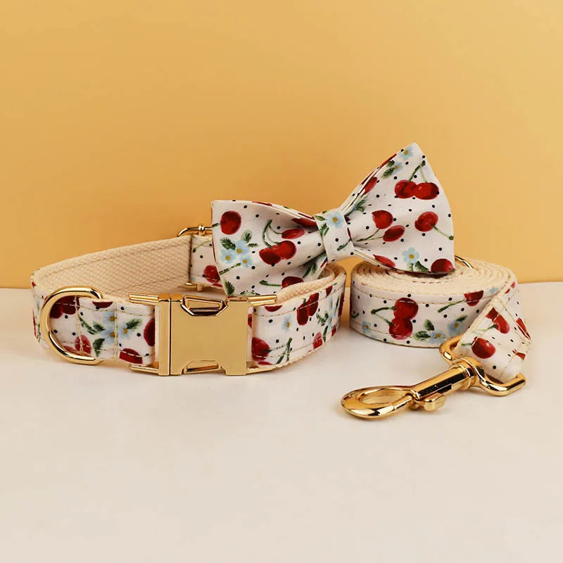 Dog collar, bow tie, and leash with cherry pattern on a beige background
