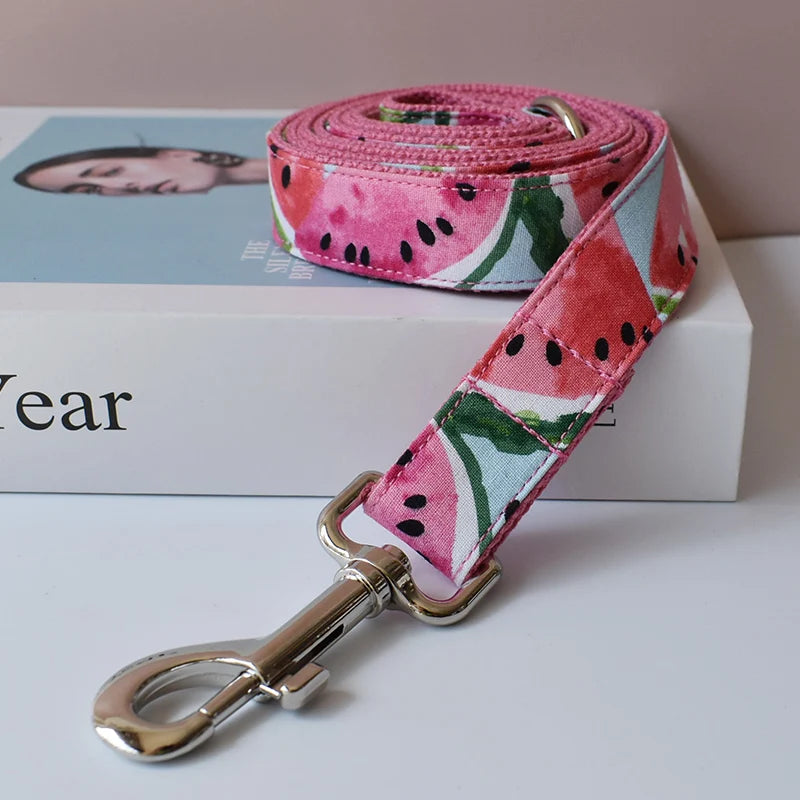 Pink watermelon patterned dog leash on a white surface with a magazine in the background.