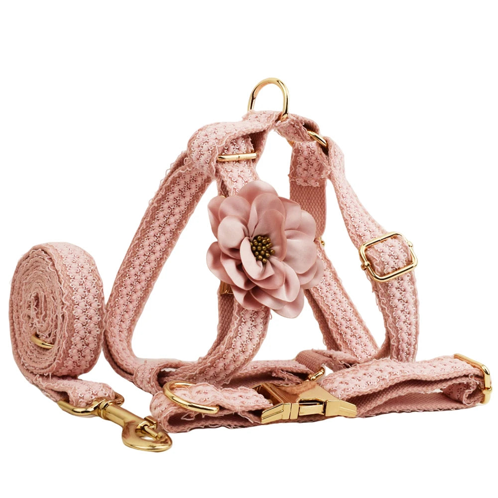 Pink dog harness with floral design and gold hardware on a white background