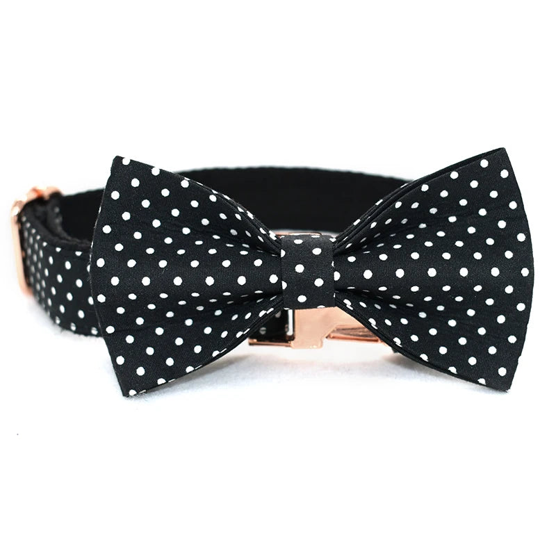 Black polka dot bow tie with a rose gold clasp on a white background