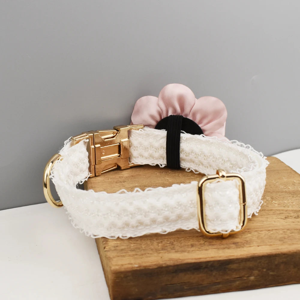 Dog collar with lace detailing and gold buckle on a wooden block against a gray background