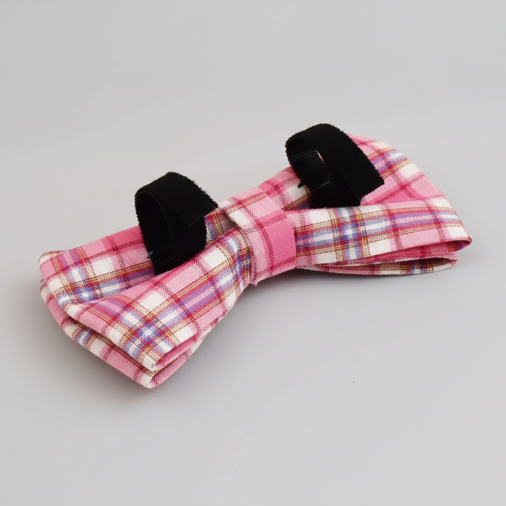 Pink plaid bow tie with black straps on a light gray background