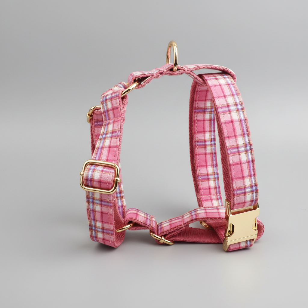 Pink plaid dog harness with gold hardware on a gray background