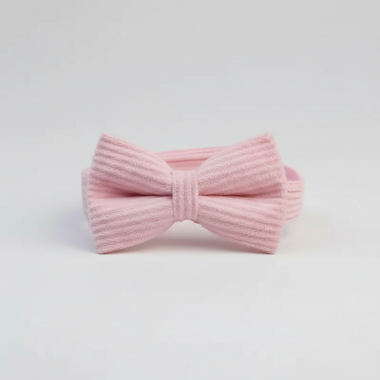 Pink knitted bow tie on a light gray background