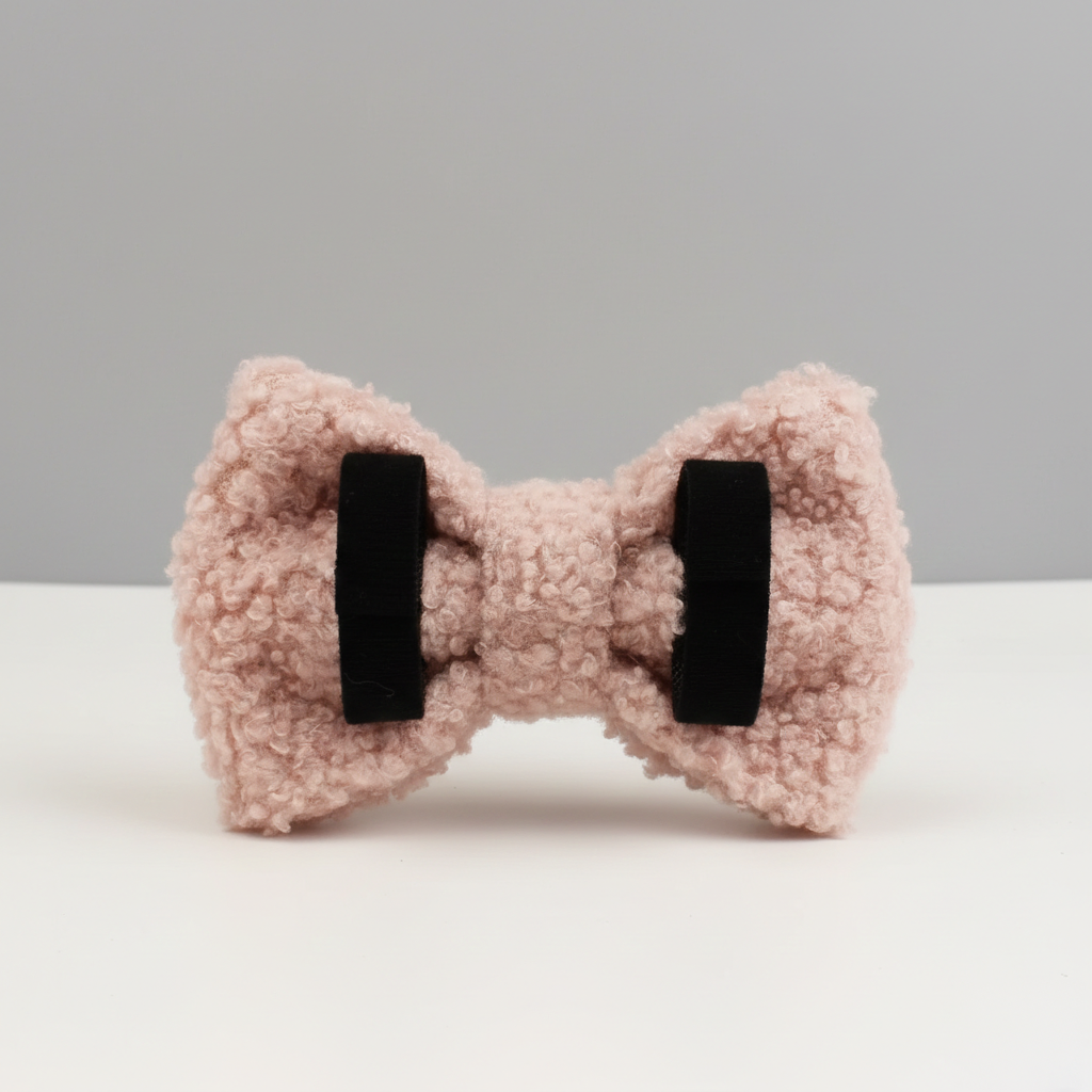 A pink dog bow on a white table with a gray wall behind it, facing backwards