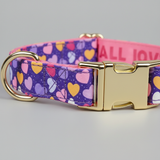 Dog collar with colorful heart pattern and gold buckle on a gray background