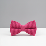 Pink bow tie on a white surface with a gray background