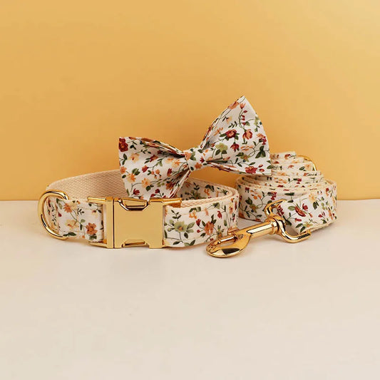 Floral dog collar, bow tie, and leash set on a beige surface with a yellow background