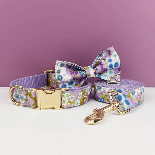 Floral dog collar, bow tie, and leash set on a white surface with a purple background