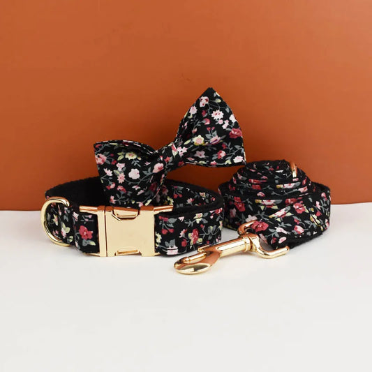 Floral dog collar, leash, and bow tie set on a white surface with an orange background