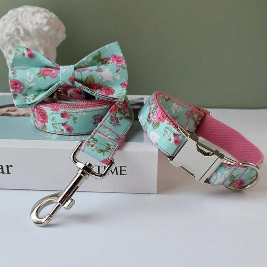 Floral dog collar, leash, and bow tie set on a book with a gray background