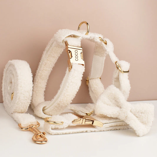White dog harness with gold hardware on a beige background
