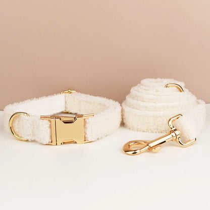 White fluffy dog collar and leash set with gold hardware on a beige background