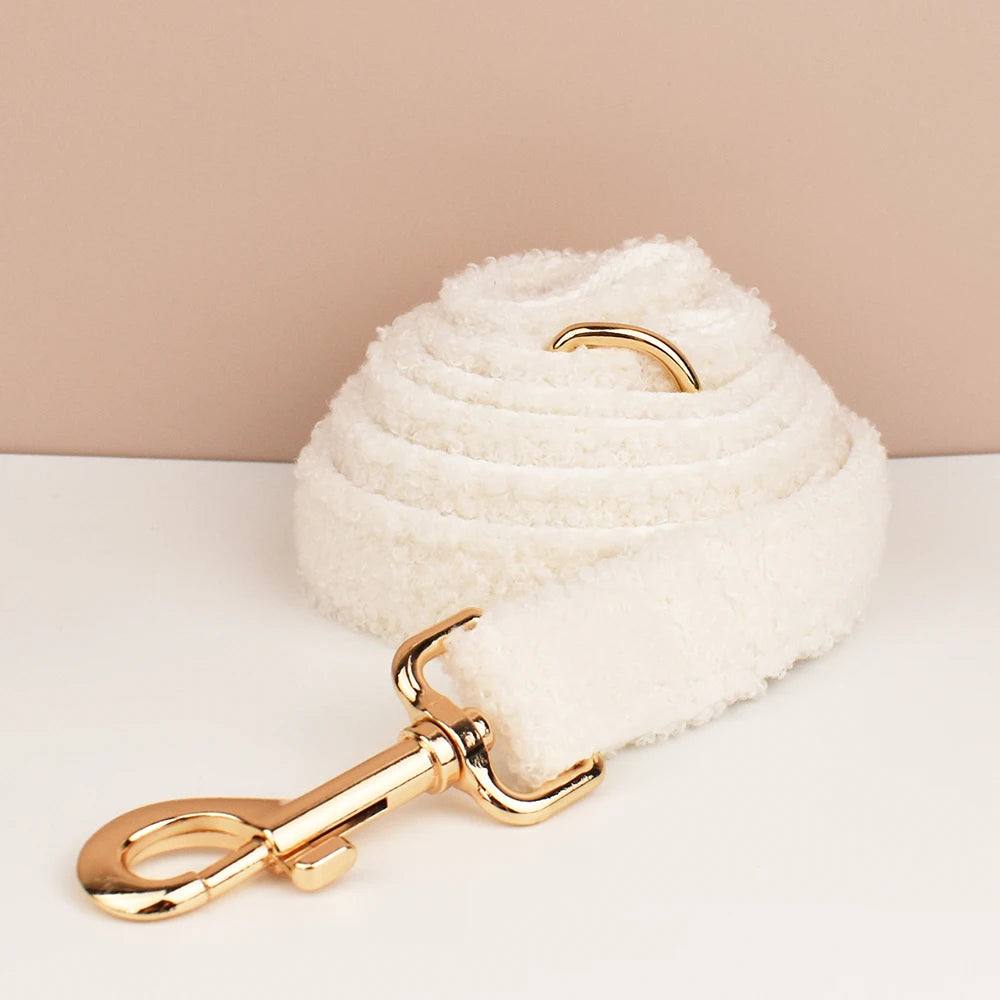 White fluffy dog leash with gold metal clip on a beige background