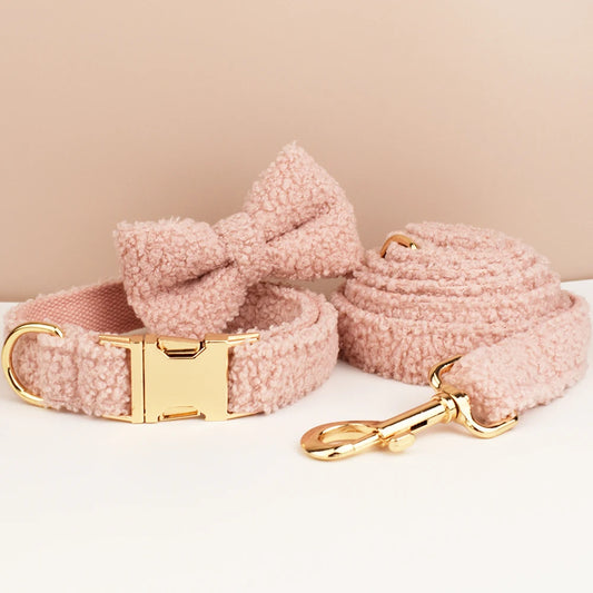 Pink dog collar and leash set with gold hardware on a beige background