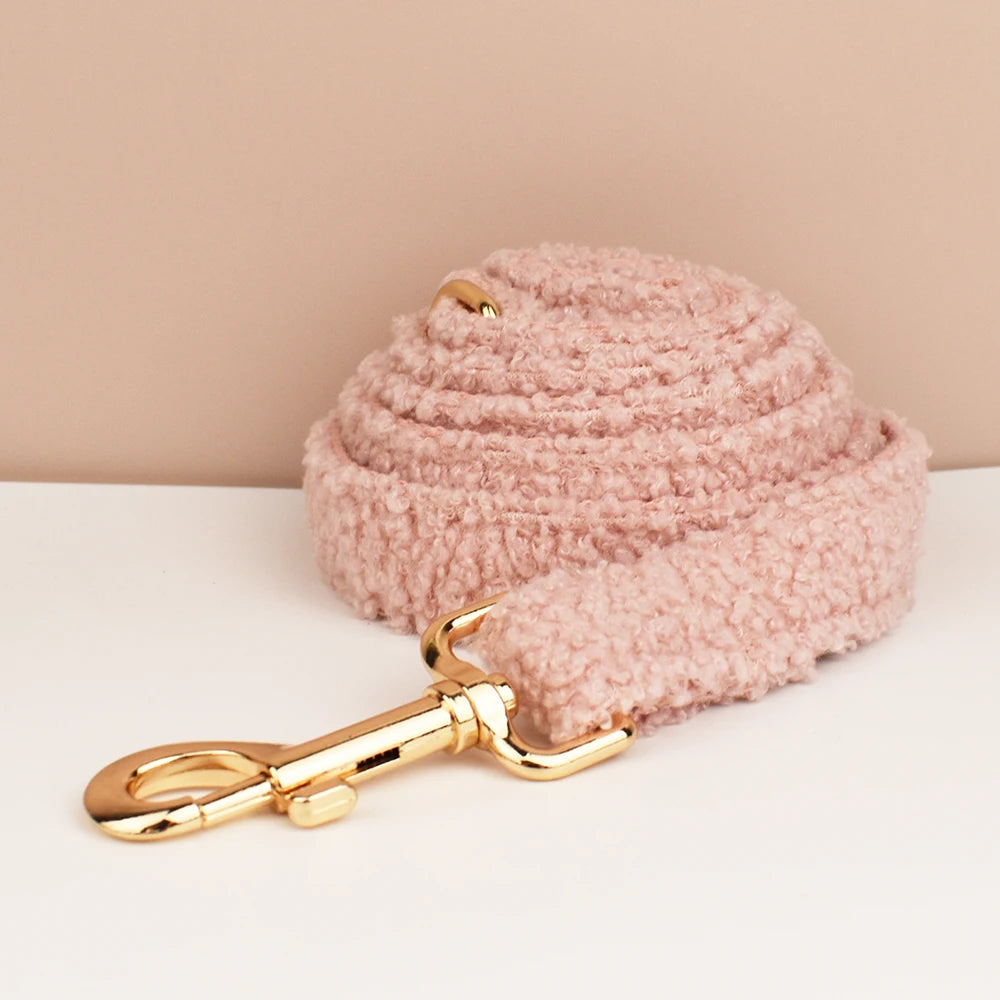 Pink textured dog leash with gold clip on a beige background