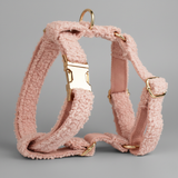 Pink dog harness with gold hardware on a gray background
