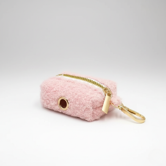Pink fuzzy pouch with gold zipper and clip on a light gray background
