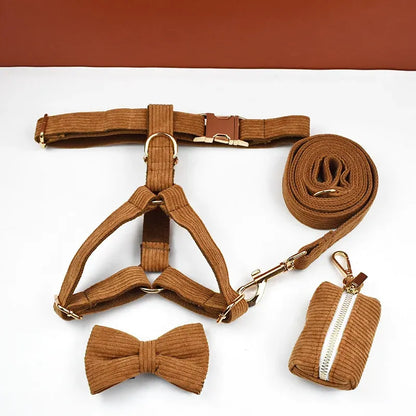 Brown dog harness, bow tie, leash, and poop bag set on a white background