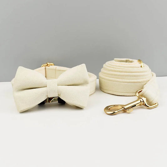 Cream-colored dog bow tie and leash set on a light gray background