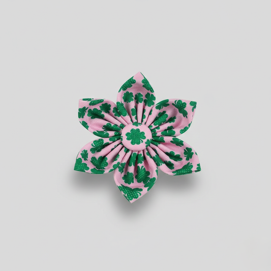Pink flower-shaped hair clip with green shamrock patterns on a light gray background