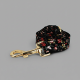 Floral-patterned dog leash with gold hardware on a gray background