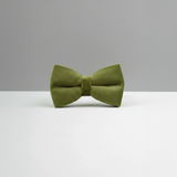 Green bow tie on a white surface with a gray background