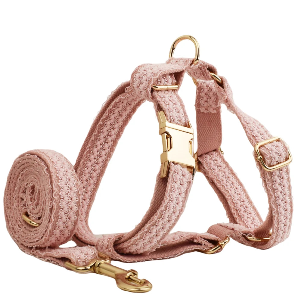 Pink dog harness and leash set with gold hardware on a white background