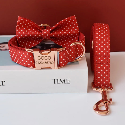 Red polka dot dog collar with bow tie and rose gold hardware on a white surface.