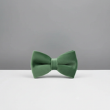 Green bow tie on a white surface with a gray background