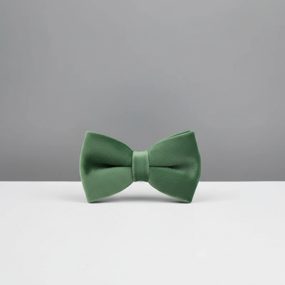 Green bow tie on a white surface with a gray background