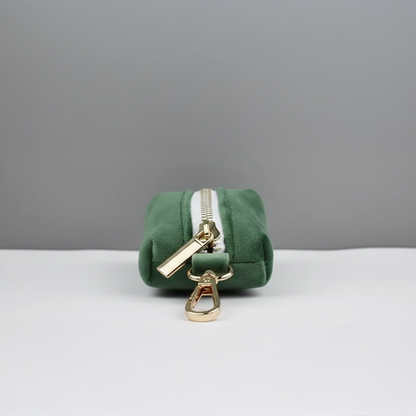 Green pouch with gold zipper and clasp on a gray background