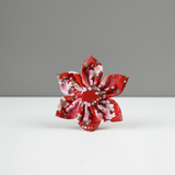 Red and white floral-patterned brooch on a gray background