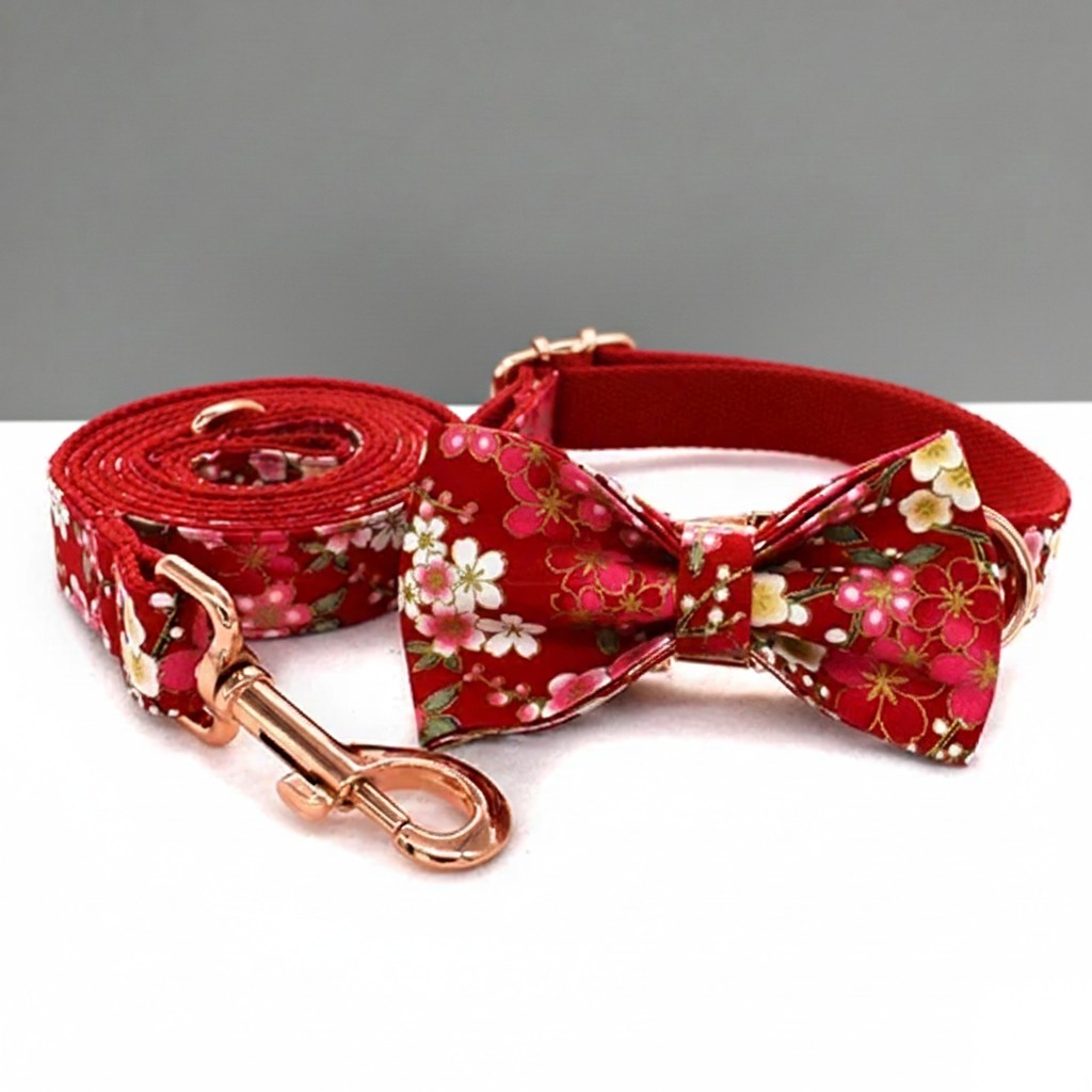 Red floral dog collar, bow tie, and leash set on a white surface with a gray background