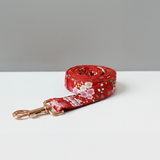 Red floral dog leash on a white surface with a gray background
