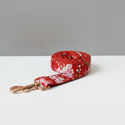 Red floral dog leash on a white surface with a gray background