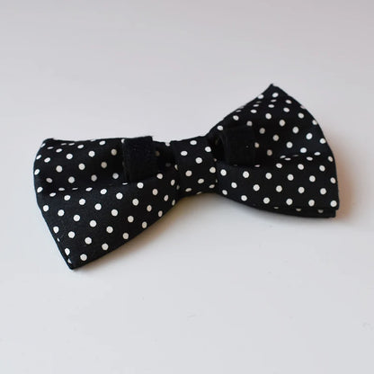 Black bow tie with white polka dots on a light gray background