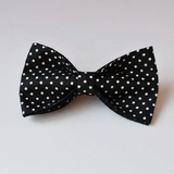 Black bow tie with white polka dots on a light gray background
