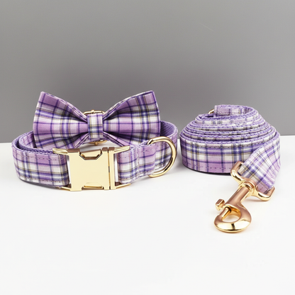 Purple plaid dog collar, leash, and bow tie set on a gray background