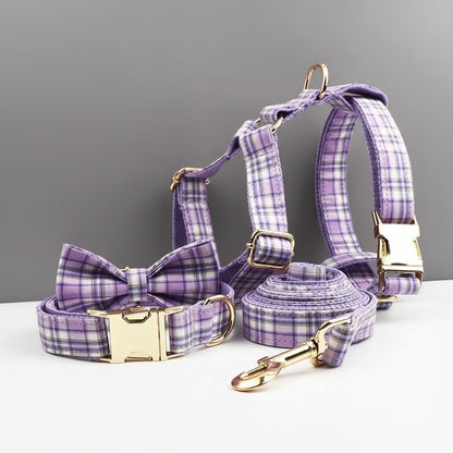 Purple plaid dog collar, harness, and leash set on a gray background