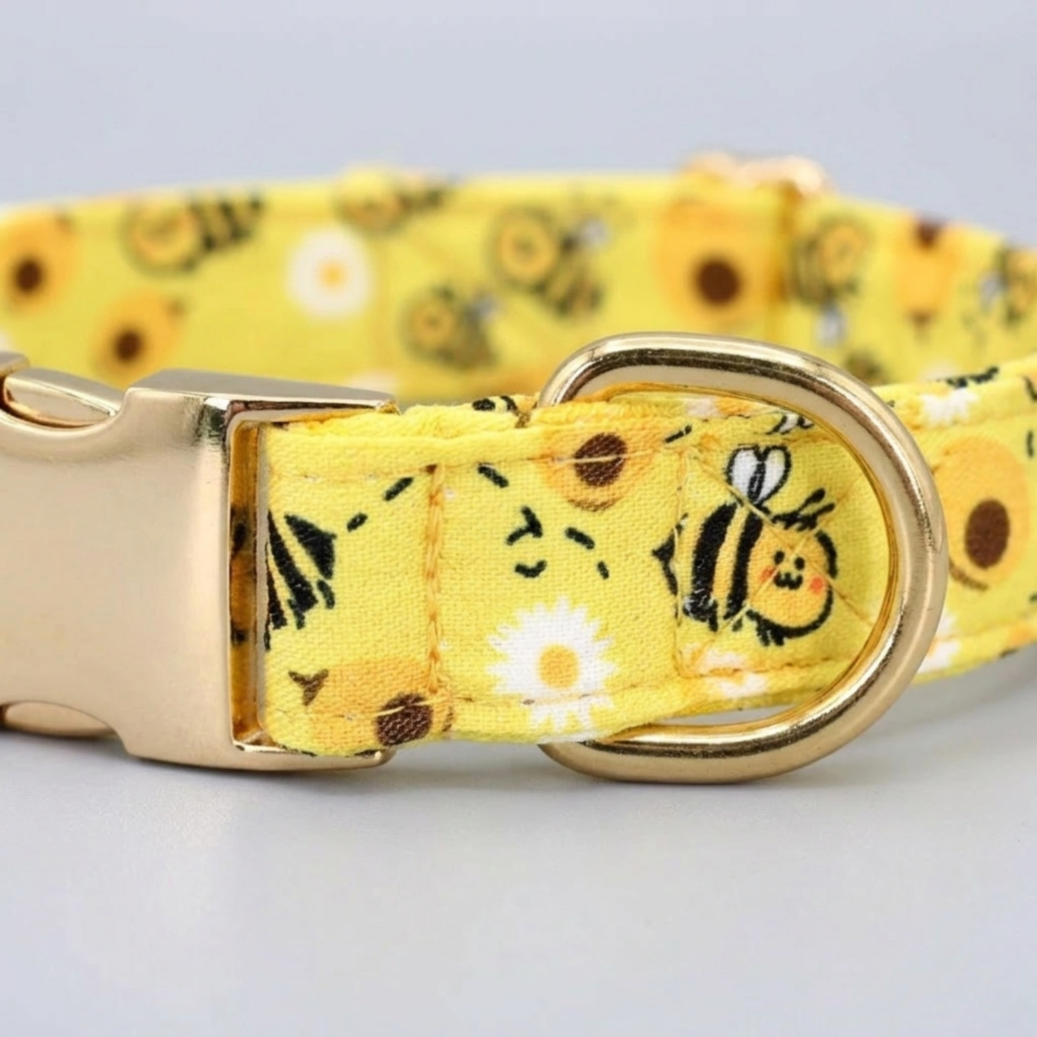 Yellow dog collar with bee and flower pattern on a light gray background