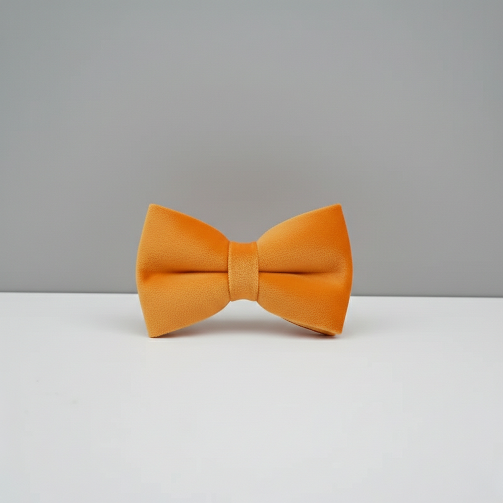 Orange bow tie on a white surface with a gray background