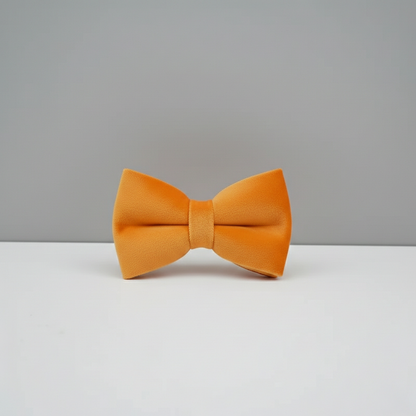 Orange bow tie on a white surface with a gray background