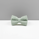 Light green ribbed bow tie on a white surface with a gray background