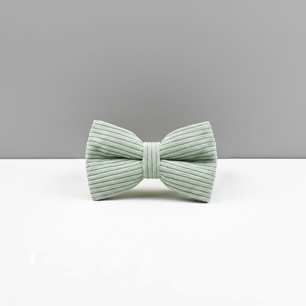 Light green ribbed bow tie on a white surface with a gray background